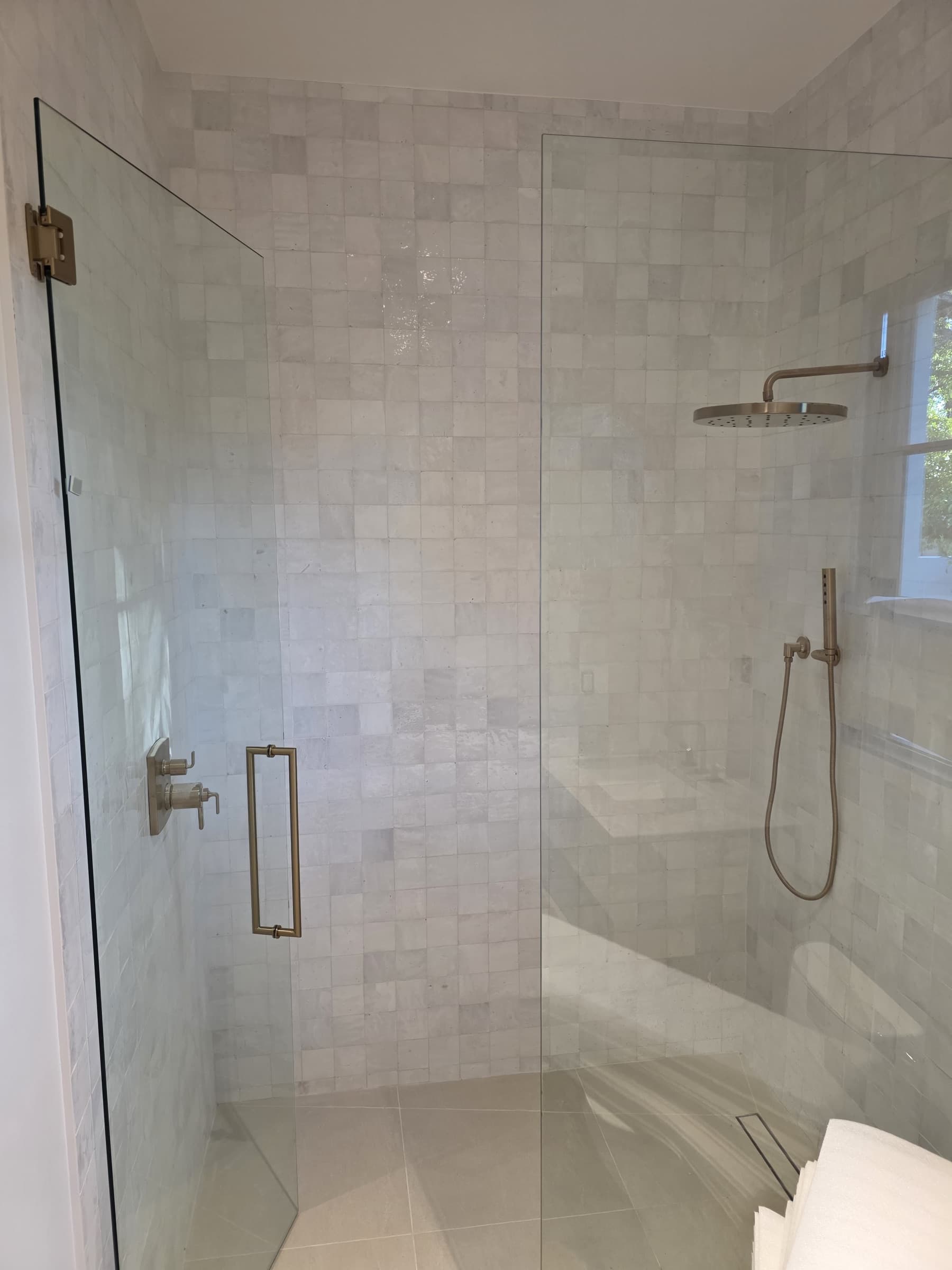 Frameless glass walk-in shower with handmade white tile